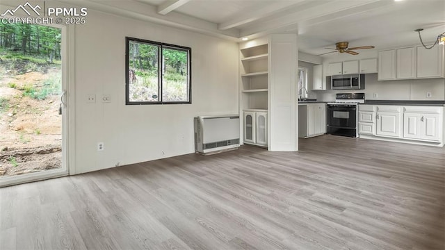 900 Beaver Creek Dr, Florissant, CO 80816 - unfurnished living room with wood finished floors, heating unit, ceiling fan, beamed ceiling, and a sink