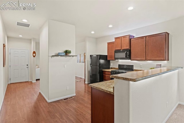 10067 Seawolf Dr, Colorado Springs, CO 80925 - kitchen with black appliances, brown cabinetry, baseboards, a peninsula, and light wood finished floors