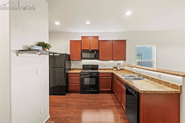 10067 Seawolf Dr, Colorado Springs, CO 80925 - kitchen with black appliances, a sink, wood finished floors, a peninsula, and light countertops