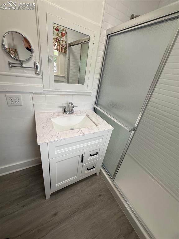 506 S Hancock Ave, Colorado Springs, CO 80903 - full bath featuring vanity, wood finished floors, a shower stall, and baseboards