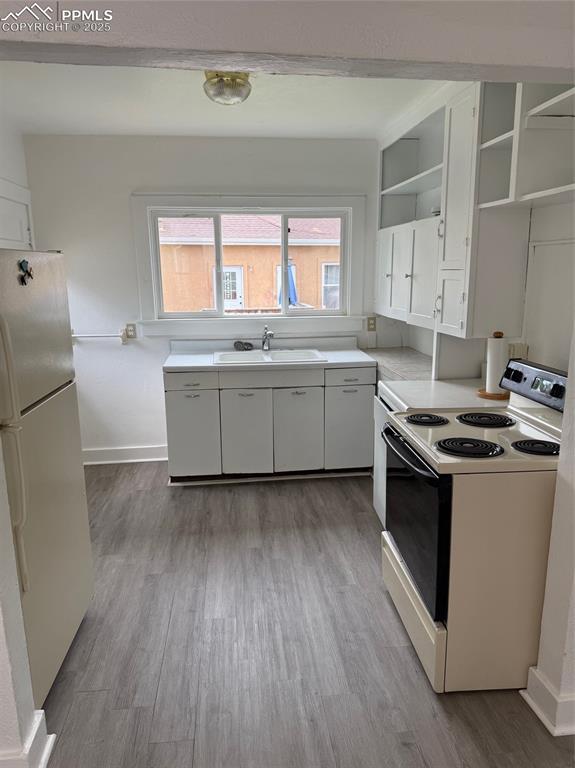 506 S Hancock Ave, Colorado Springs, CO 80903 - kitchen with white appliances, open shelves, a sink, white cabinetry, and wood finished floors