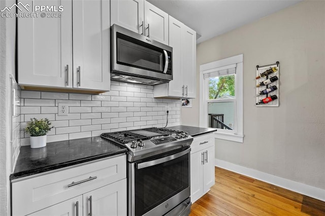 421 N Spruce St, Colorado Springs, CO 80905 - kitchen with stainless steel appliances, decorative backsplash, light wood finished floors, baseboards, and white cabinets