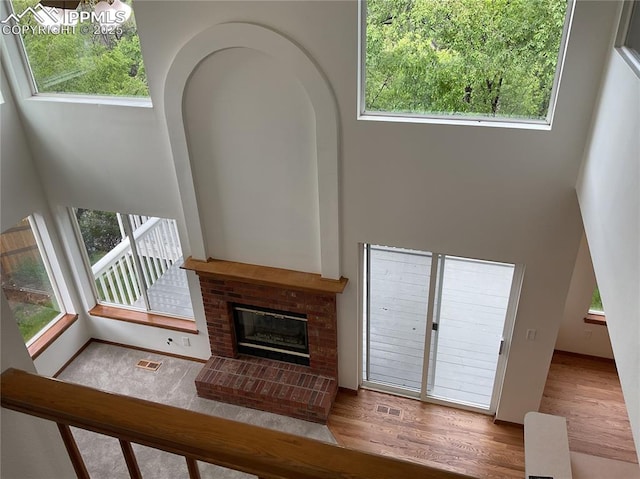 1185 Marlstone Pl, Colorado Springs, CO 80904 - unfurnished living room with wood finished floors, a fireplace, healthy amount of natural light, and a towering ceiling