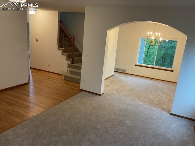 1185 Marlstone Pl, Colorado Springs, CO 80904 - carpeted empty room featuring arched walkways, stairs, a chandelier, and wood finished floors