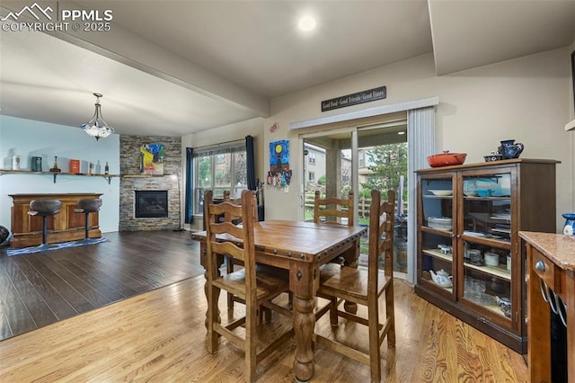 2374 Cinnabar Rd, Colorado Springs, CO 80921 - dining space featuring wood finished floors, a stone fireplace, and beam ceiling