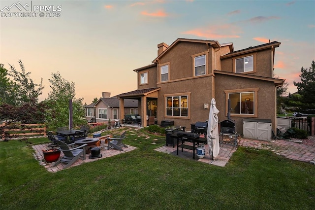 2374 Cinnabar Rd, Colorado Springs, CO 80921 - back of house at dusk featuring a fire pit, a patio, a chimney, and stucco siding