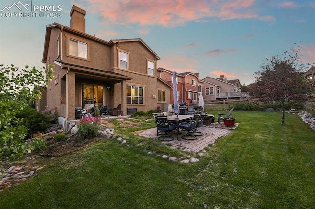 2374 Cinnabar Rd, Colorado Springs, CO 80921 - back of house at dusk with a chimney, a patio area, and stucco siding