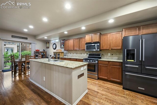 2374 Cinnabar Rd, Colorado Springs, CO 80921 - kitchen with stainless steel appliances, light wood finished floors, brown cabinets, recessed lighting, and decorative backsplash
