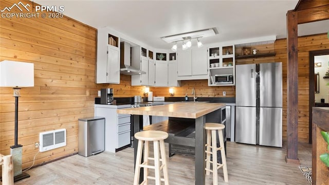 145 Valley Ln, Woodland Park, CO 80863 - kitchen with stainless steel appliances, wood walls, wooden counters, wall chimney exhaust hood, and a sink