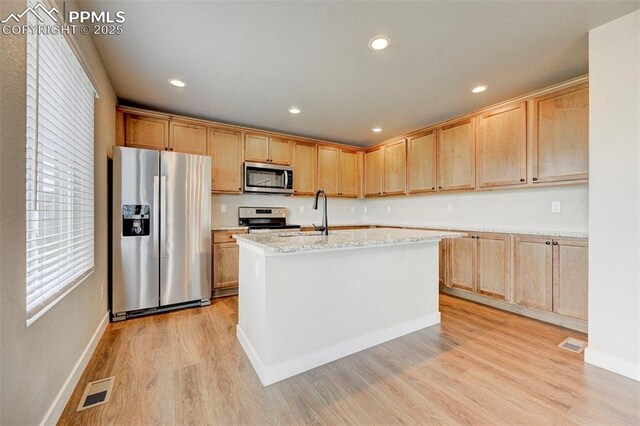 6967 Akela Ln, Colorado Springs, CO 80925 - kitchen with appliances with stainless steel finishes, light wood-style flooring, baseboards, a kitchen island with sink, and a sink