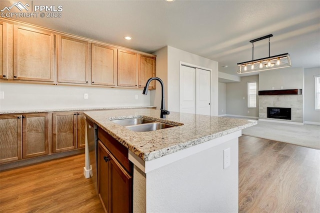6967 Akela Ln, Colorado Springs, CO 80925 - kitchen featuring a sink, light wood finished floors, hanging light fixtures, a tile fireplace, and recessed lighting