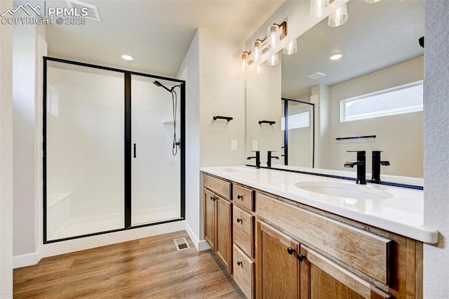 6967 Akela Ln, Colorado Springs, CO 80925 - bathroom featuring a shower stall, double vanity, wood finished floors, recessed lighting, and baseboards
