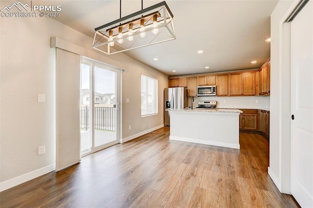 6967 Akela Ln, Colorado Springs, CO 80925 - kitchen featuring appliances with stainless steel finishes, wood finished floors, brown cabinetry, light countertops, and recessed lighting
