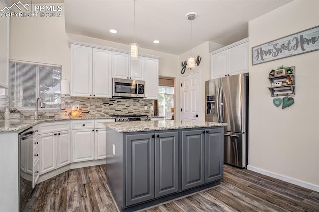 16084 Stonebriar Dr, Parker, CO 80134 - kitchen featuring appliances with stainless steel finishes, a center island, a sink, white cabinetry, and backsplash