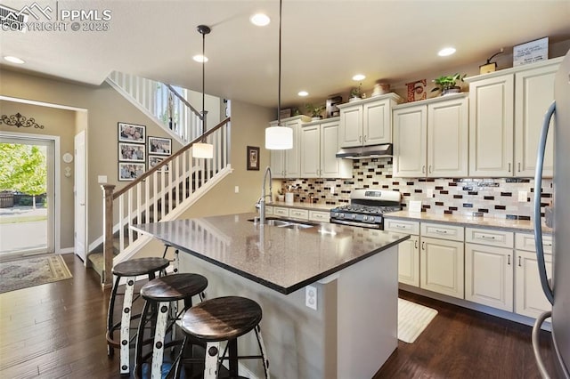 1593 Gold Hill Mesa Dr, Colorado Springs, CO 80905 - kitchen with stainless steel range with gas stovetop, under cabinet range hood, tasteful backsplash, dark wood-style floors, and recessed lighting