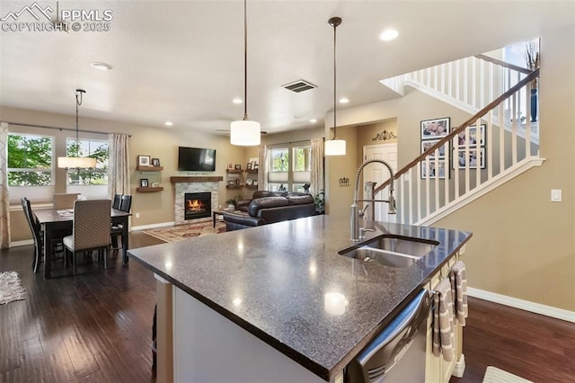 1593 Gold Hill Mesa Dr, Colorado Springs, CO 80905 - kitchen featuring dishwasher, a lit fireplace, dark wood finished floors, a kitchen island with sink, and recessed lighting