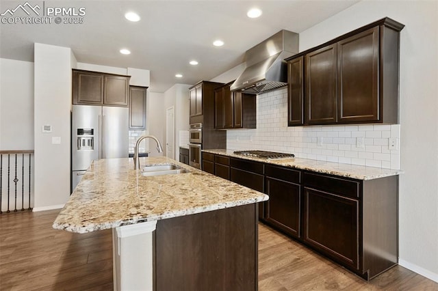 10897 Hidden Brook Cir, Colorado Springs, CO 80908 - kitchen with wall chimney exhaust hood, appliances with stainless steel finishes, a sink, light stone counters, and dark brown cabinetry