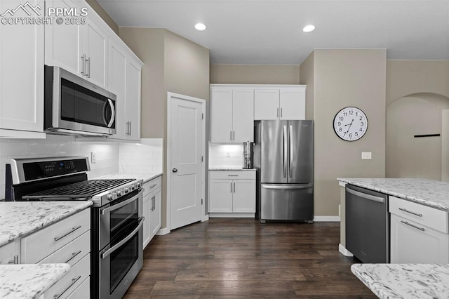 1734 Summerglow Ln, Monument, CO 80132 - kitchen featuring stainless steel appliances, white cabinetry, tasteful backsplash, arched walkways, and light stone countertops