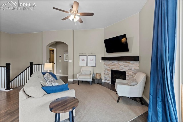 1734 Summerglow Ln, Monument, CO 80132 - living area with arched walkways, dark wood-type flooring, a ceiling fan, and baseboards