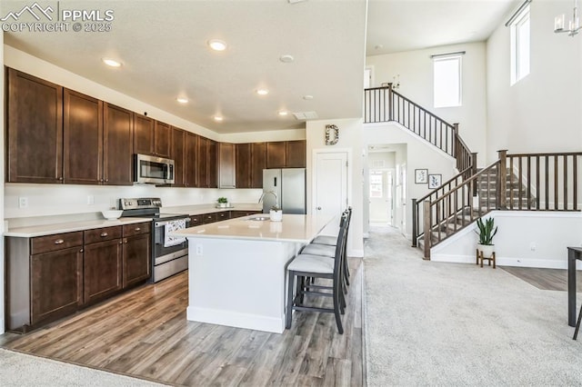 1842 Peak Prairie Ln, Monument, CO 80132 - kitchen featuring appliances with stainless steel finishes, light countertops, dark brown cabinets, a center island with sink, and recessed lighting