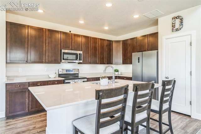 1842 Peak Prairie Ln, Monument, CO 80132 - kitchen featuring stainless steel appliances, a breakfast bar area, light wood-style floors, a center island with sink, and recessed lighting