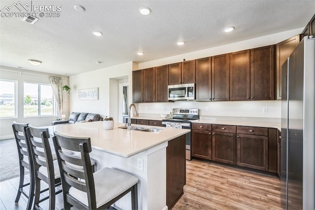 1842 Peak Prairie Ln, Monument, CO 80132 - kitchen featuring stainless steel appliances, light countertops, a textured ceiling, a breakfast bar, and open floor plan