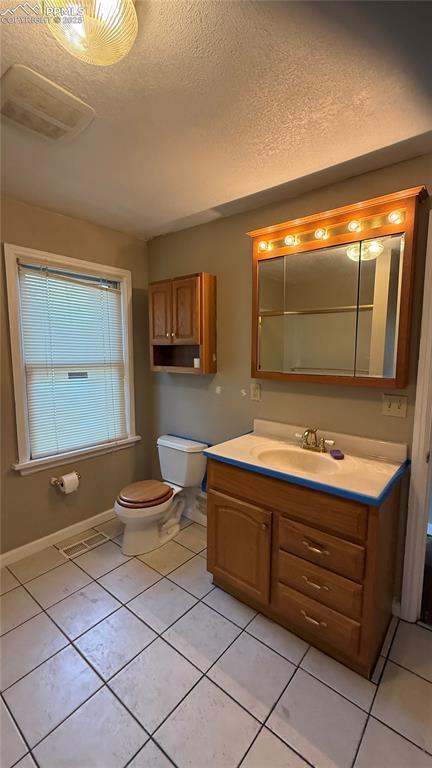 5030 Beach Ct, Denver, CO 80221 - bathroom featuring toilet, vanity, tile patterned floors, a textured ceiling, and baseboards