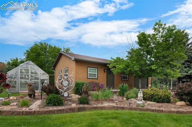 3512 Chico Cir, Colorado Springs, CO 80918 - view of side of property with a greenhouse, a yard, stucco siding, and an outbuilding