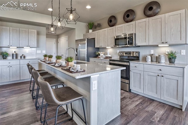 7703 Lost Trail Dr, Colorado Springs, CO 80908 - kitchen featuring stainless steel appliances, a sink, a kitchen island with sink, decorative backsplash, and a kitchen bar
