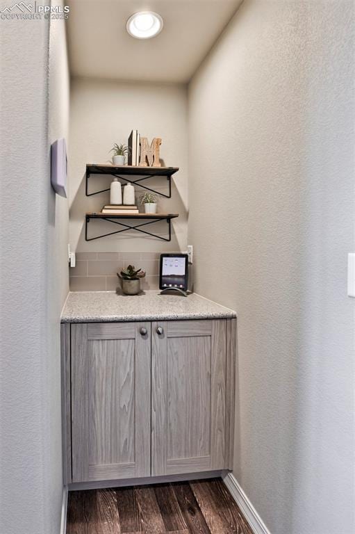 7703 Lost Trail Dr, Colorado Springs, CO 80908 - bar with dark wood-type flooring, tasteful backsplash, and baseboards
