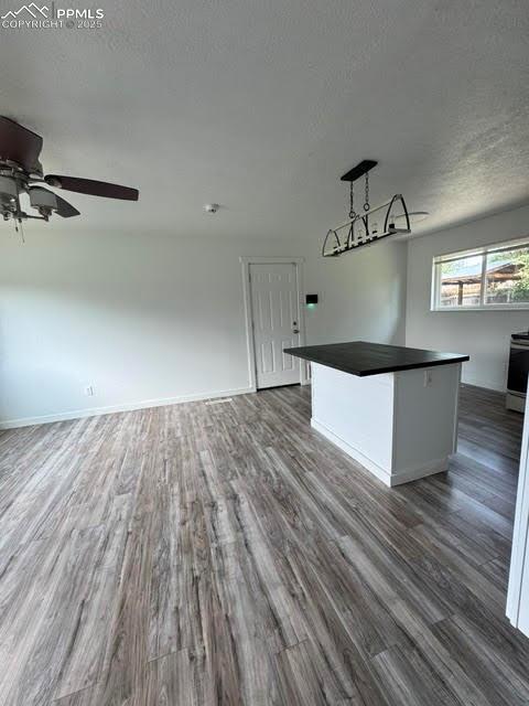 4425 Barkman Cir, Colorado Springs, CO 80916 - unfurnished living room with wood finished floors, a ceiling fan, a textured ceiling, and baseboards