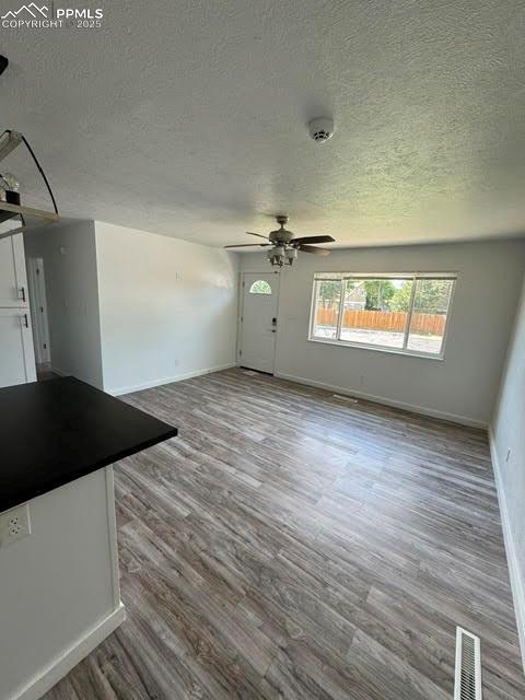 4425 Barkman Cir, Colorado Springs, CO 80916 - unfurnished living room with a textured ceiling, baseboards, wood finished floors, and ceiling fan