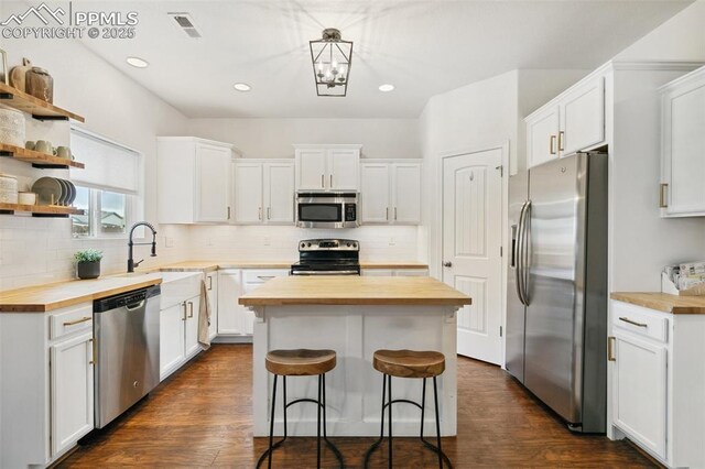 3748 Reindeer Cir, Colorado Springs, CO 80922 - kitchen featuring wooden counters, stainless steel appliances, a center island, a sink, and white cabinets