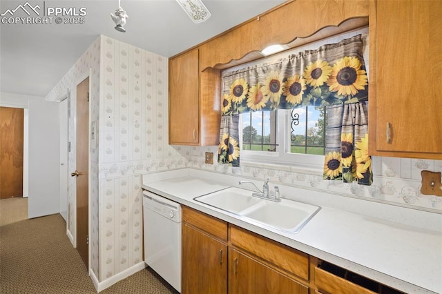 2043 Patrician Way, Colorado Springs, CO 80909 - kitchen featuring white dishwasher, a sink, light countertops, wallpapered walls, and brown cabinetry