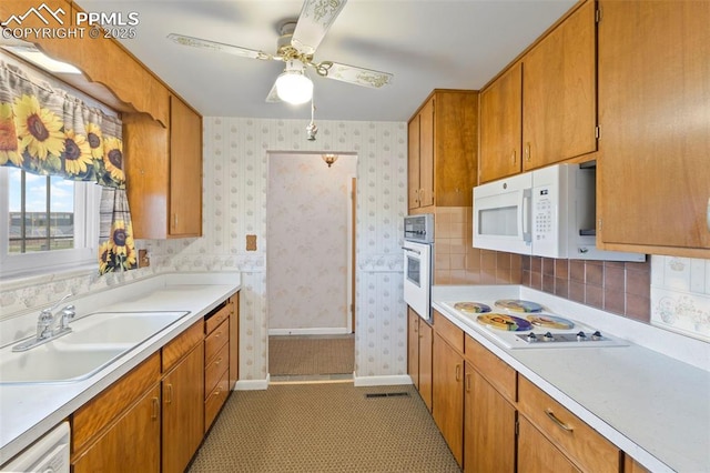 2043 Patrician Way, Colorado Springs, CO 80909 - kitchen with white appliances, a sink, wallpapered walls, light countertops, and baseboards
