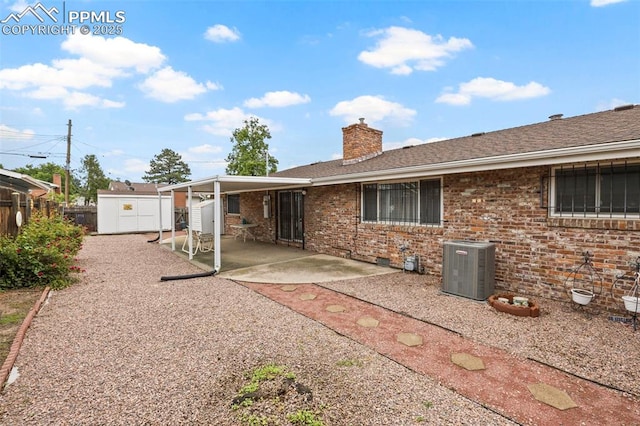 2043 Patrician Way, Colorado Springs, CO 80909 - rear view of house with cooling unit, a chimney, a patio area, brick siding, and roof with shingles