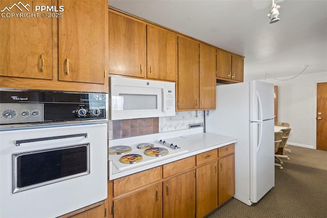 2043 Patrician Way, Colorado Springs, CO 80909 - kitchen featuring white appliances, tasteful backsplash, light countertops, and brown cabinets