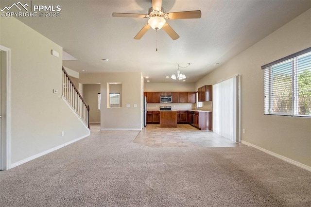 2305 Reed Grass Way, Colorado Springs, CO 80915 - kitchen with stainless steel microwave, open floor plan, light colored carpet, brown cabinets, and freestanding refrigerator