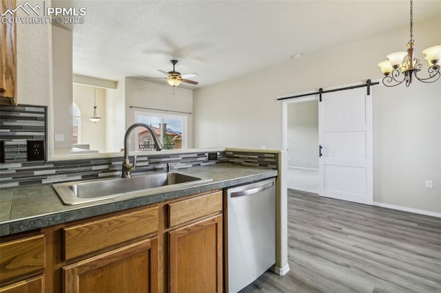4710 Sand Mountain Pt, Colorado Springs, CO 80923 - kitchen with dishwasher, a barn door, dark countertops, and decorative backsplash