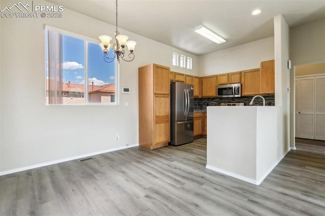 4710 Sand Mountain Pt, Colorado Springs, CO 80923 - kitchen with appliances with stainless steel finishes, a chandelier, light wood-style floors, decorative backsplash, and recessed lighting