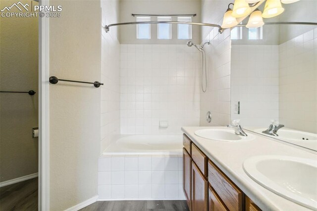 4710 Sand Mountain Pt, Colorado Springs, CO 80923 - bathroom featuring tiled shower / bath combo, double vanity, a chandelier, and wood finished floors
