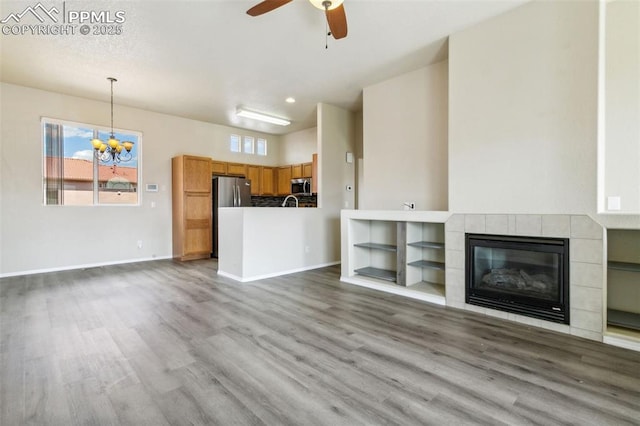 4710 Sand Mountain Pt, Colorado Springs, CO 80923 - unfurnished living room with a chandelier, wood finished floors, a ceiling fan, a tiled fireplace, and recessed lighting