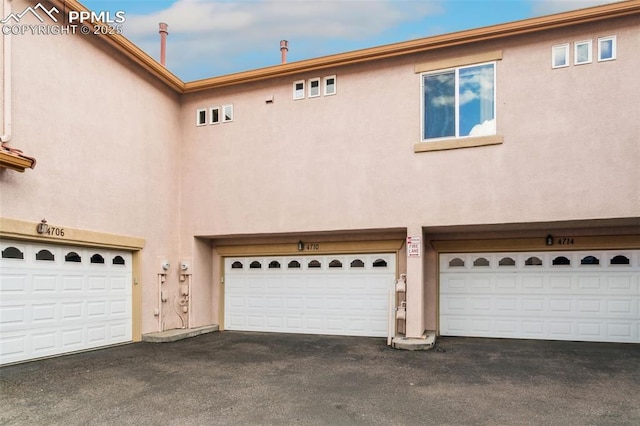 4710 Sand Mountain Pt, Colorado Springs, CO 80923 - back of house featuring stucco siding, asphalt driveway, and an attached garage