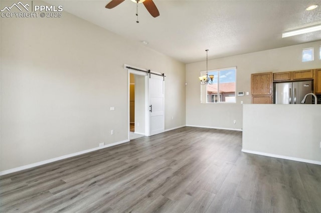 4710 Sand Mountain Pt, Colorado Springs, CO 80923 - unfurnished living room featuring a barn door, a ceiling fan, healthy amount of natural light, and dark wood-style floors