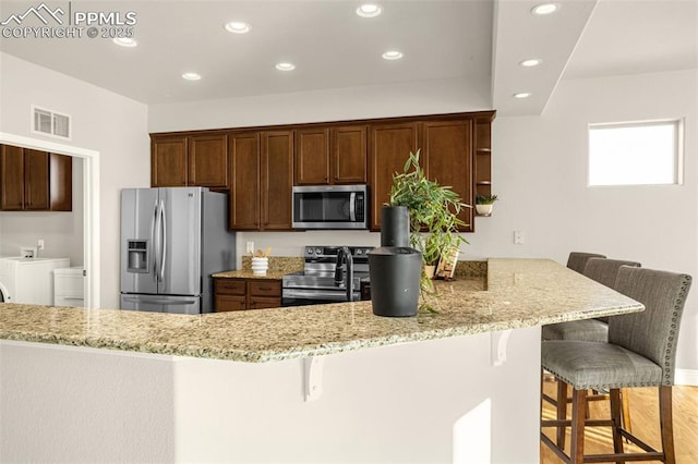 16255 Ridge Run Dr, Colorado Springs, CO 80908 - kitchen featuring appliances with stainless steel finishes, recessed lighting, light stone counters, a breakfast bar, and a peninsula