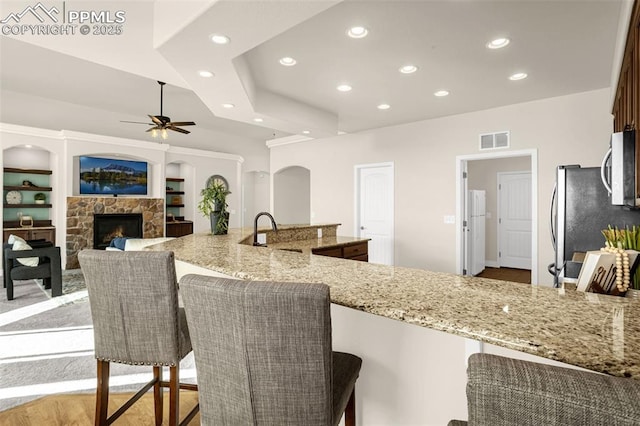 16255 Ridge Run Dr, Colorado Springs, CO 80908 - kitchen featuring recessed lighting, ceiling fan, light stone counters, stainless steel appliances, and a fireplace