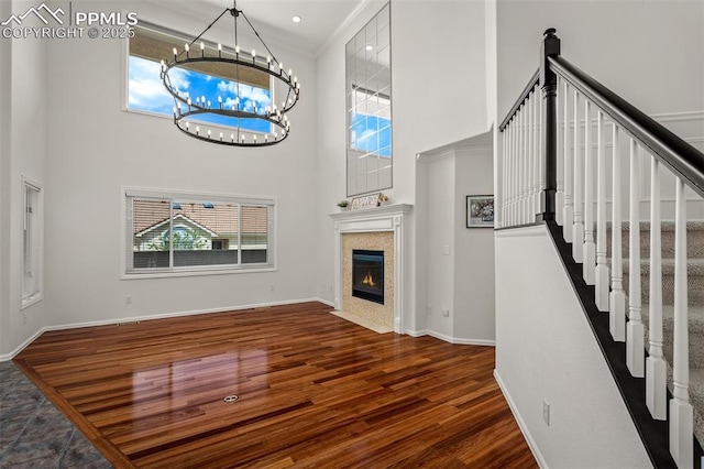 206 Luxury Ln, Colorado Springs, CO 80921 - unfurnished living room with wood finished floors, a chandelier, a high ceiling, stairs, and a fireplace