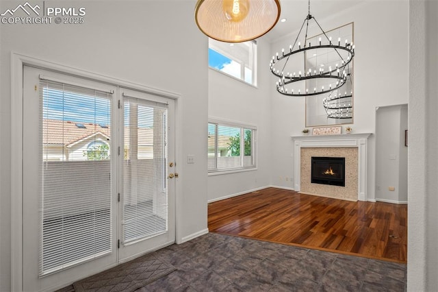206 Luxury Ln, Colorado Springs, CO 80921 - entryway with a high ceiling, a chandelier, a warm lit fireplace, wood finished floors, and crown molding