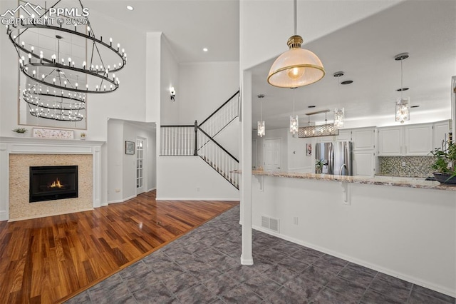 206 Luxury Ln, Colorado Springs, CO 80921 - kitchen featuring stainless steel refrigerator with ice dispenser, light stone countertops, a chandelier, dark wood finished floors, and a breakfast bar area