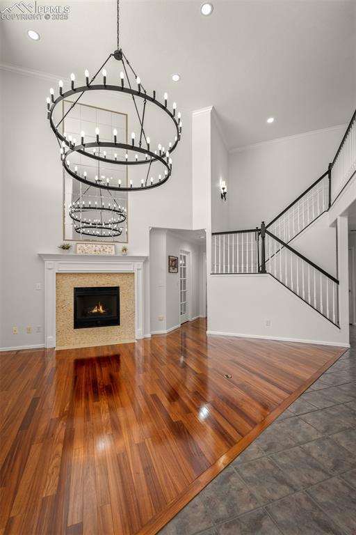 206 Luxury Ln, Colorado Springs, CO 80921 - unfurnished living room featuring a chandelier, a high ceiling, ornamental molding, stairs, and a fireplace
